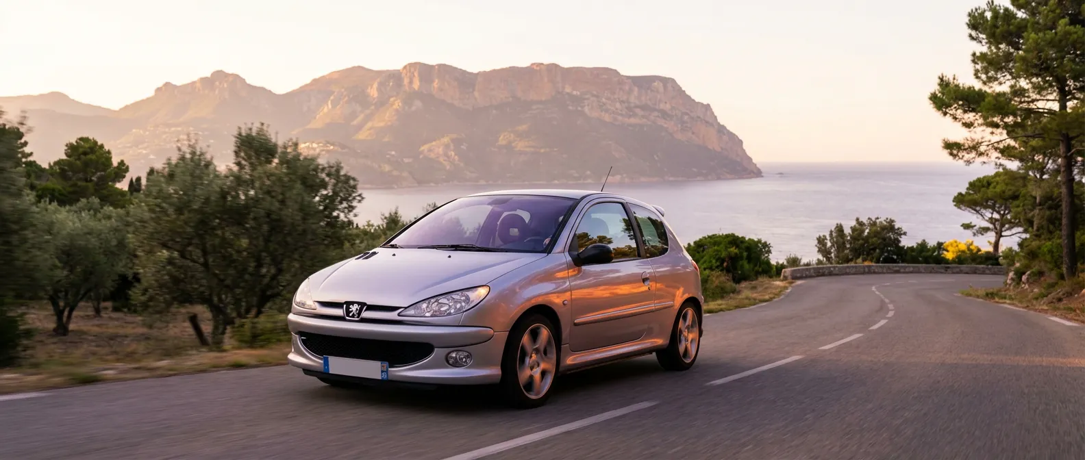 Peugeot 206 1.4 HDi roulant sur une route de corniche au coucher du soleil