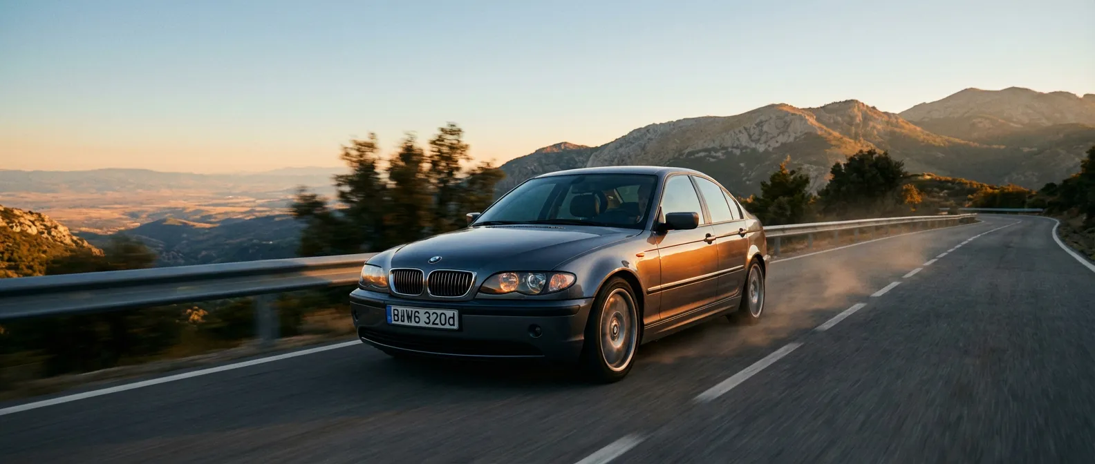 BMW E46 320d : Icône bavaroise sur route de légende BMW E46 320d grise roulant sur une route de montagne sinueuse au coucher du soleil.