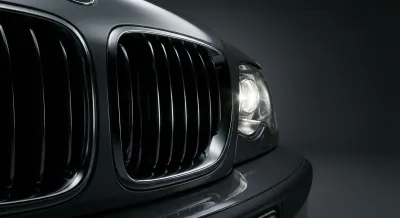 Gros plan minimaliste et contrasté sur la calandre et le phare d'une BMW E46 320d.