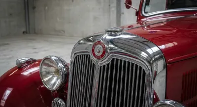 Gros plan emblématique du calandre chromé et de l'emblème d'un ancien camion de pompier français rouge, fort contraste et détails nets.