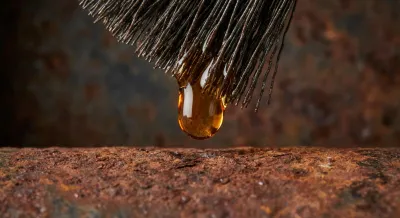 Gros plan contrasté d'une goutte de produit antirouille Rustol Owatrol sur une surface rouillée.